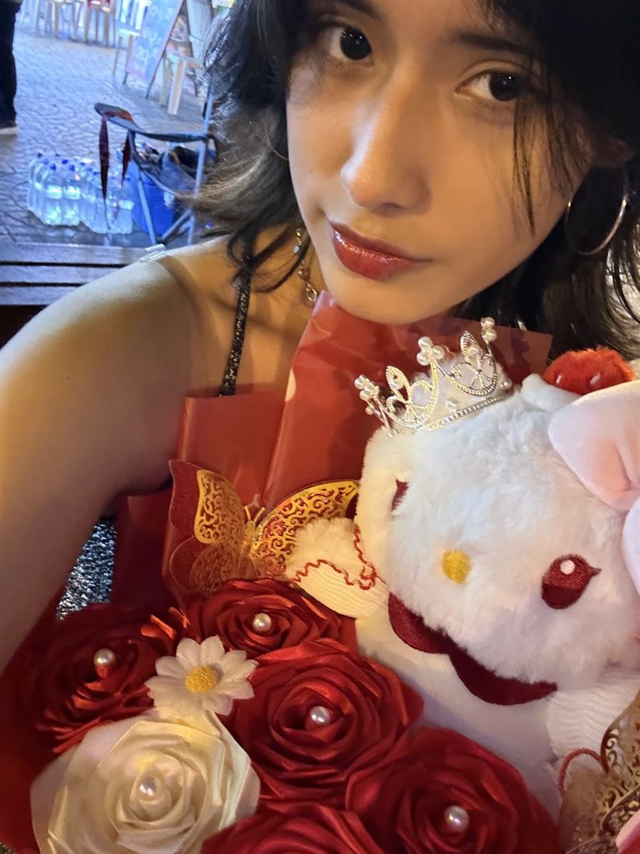 Gabi con un ramo rojo y un peluche con corona
